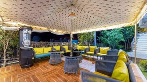 An outdoor patio with a patterned ceiling, a water dispenser, and seating with yellow cushions. - Alaya Stays By Elivaas Kingdom Heartz (Nainital)