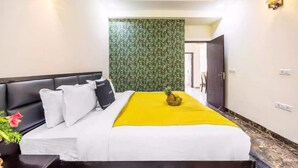 A hotel room with a bed, a nightstand, a wall-mounted light, and a door. - Alaya Stays By Elivaas Kingdom Heartz (Nainital)