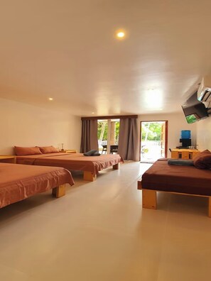 Une chambre d’hôtel avec deux lits, un téléviseur à écran plat fixé au mur et une vue sur l’extérieur par la fenêtre.
