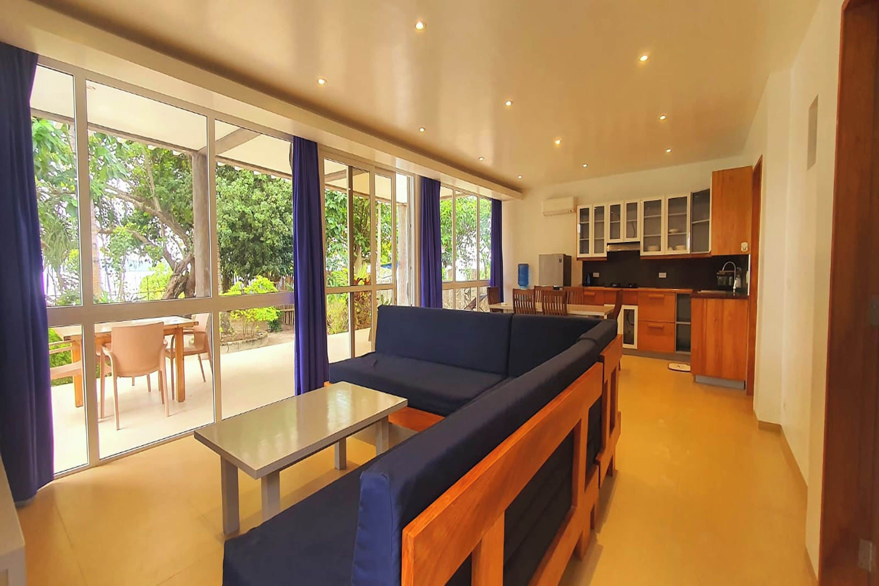 Un espacio moderno con sofá, una mesita y vistas al exterior a través de amplias ventanas.