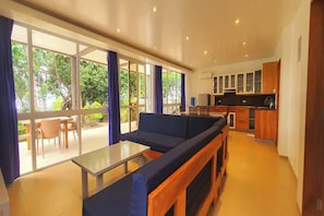 Un espacio moderno con sofá, una mesita y vistas al exterior a través de amplias ventanas.
