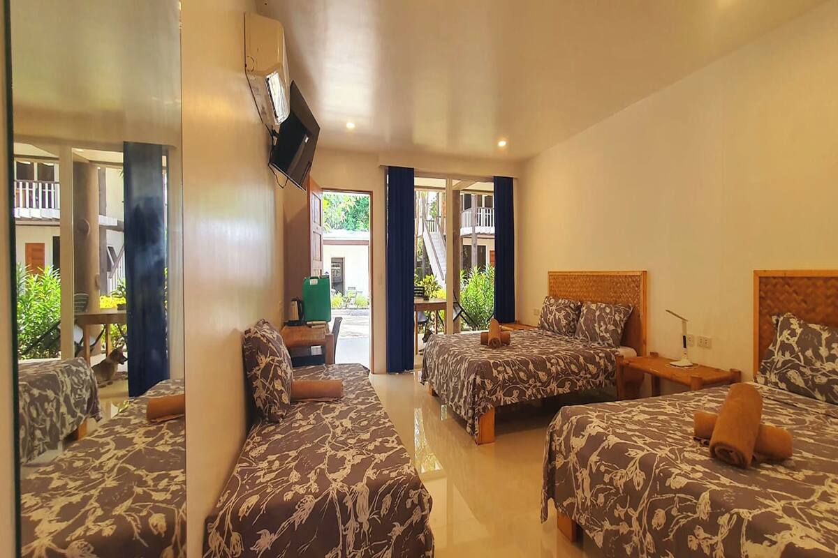 Une chambre d’hôtel avec deux lits, un téléviseur fixé au mur et un balcon donnant sur un paysage verdoyant.