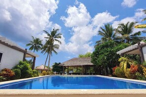 Une piscine, avec un ciel bleu azur et des palmiers en arrière-plan.