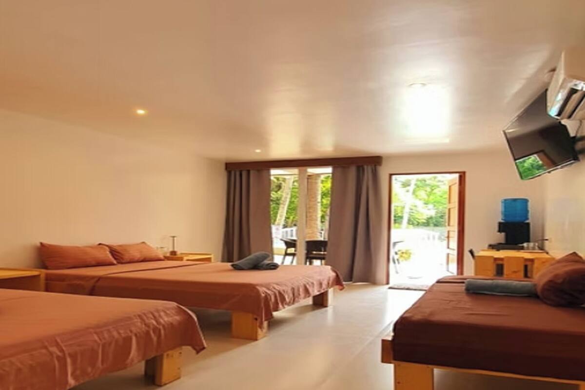 Une chambre d’hôtel avec deux lits, un téléviseur à écran plat fixé au mur et une vue sur l’extérieur par la fenêtre.