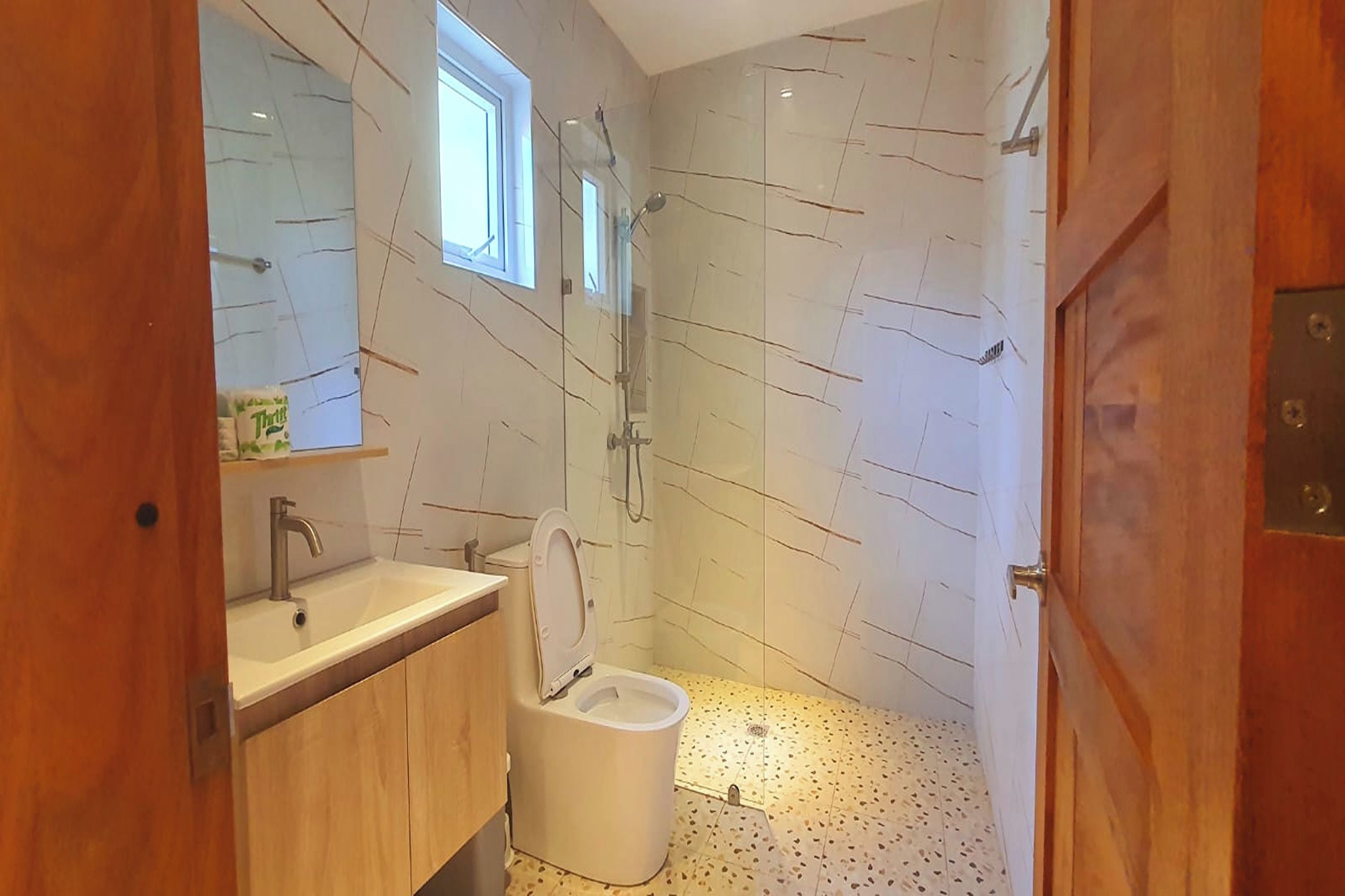 A modern bathroom with a shower, toilet, and sink.