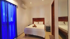 A hotel room with a large bed, a nightstand, a wooden headboard, and a mirror on the wall. - Pili Beach Resort Agmanic By Zuzu (Santa Fe)