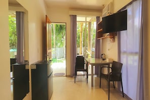A compact hotel room with a kitchenette, a dining area, and a TV mounted on the wall. - Pili Beach Resort Agmanic By Zuzu (Santa Fe)