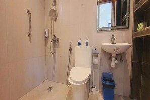 A modern bathroom with a toilet, shower, sink, and a blue trash bin. - Pili Beach Resort Agmanic By Zuzu (Santa Fe)