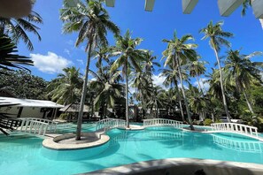 A pool area with palm trees and a clear blue sky. - Pili Beach Resort Agmanic By Zuzu (Santa Fe)