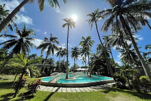 A swimming pool surrounded by palm trees under a clear sky. - Pili Beach Resort Agmanic By Zuzu (Santa Fe)