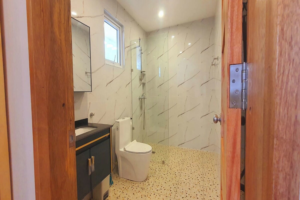 A bathroom with a toilet, a sink, a mirror, and a shower.