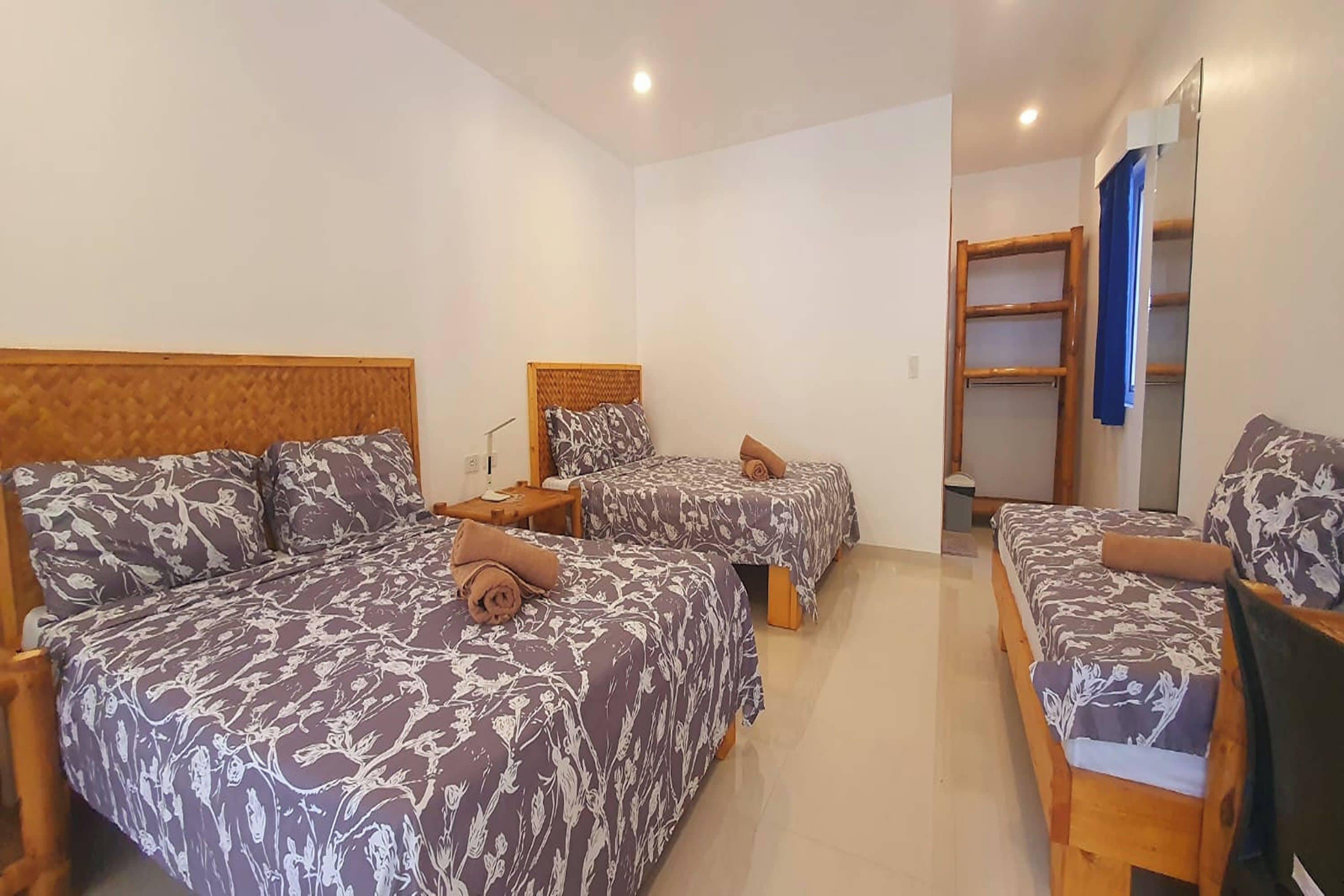 Camera d'albergo con due letti, ognuno con testiera e cuscini, un comodino e uno specchio.
