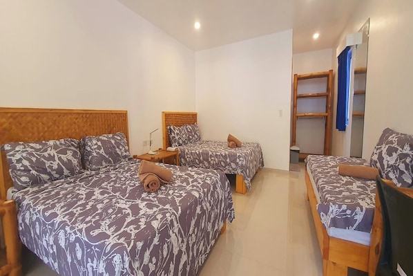 A hotel room with two beds, each with a headboard and pillows, a bedside table, and a mirror. - Pili Beach Resort Agmanic By Zuzu (Santa Fe)