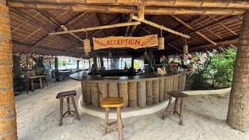 Un área de recepción con techo de bambú, un letrero que dice “Mabuhay Reception Welcome” y una barra con taburetes.