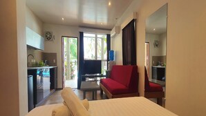 A hotel room with a bed, a red sofa, a TV, and a kitchenette. - Pili Beach Resort Agmanic By Zuzu (Santa Fe)