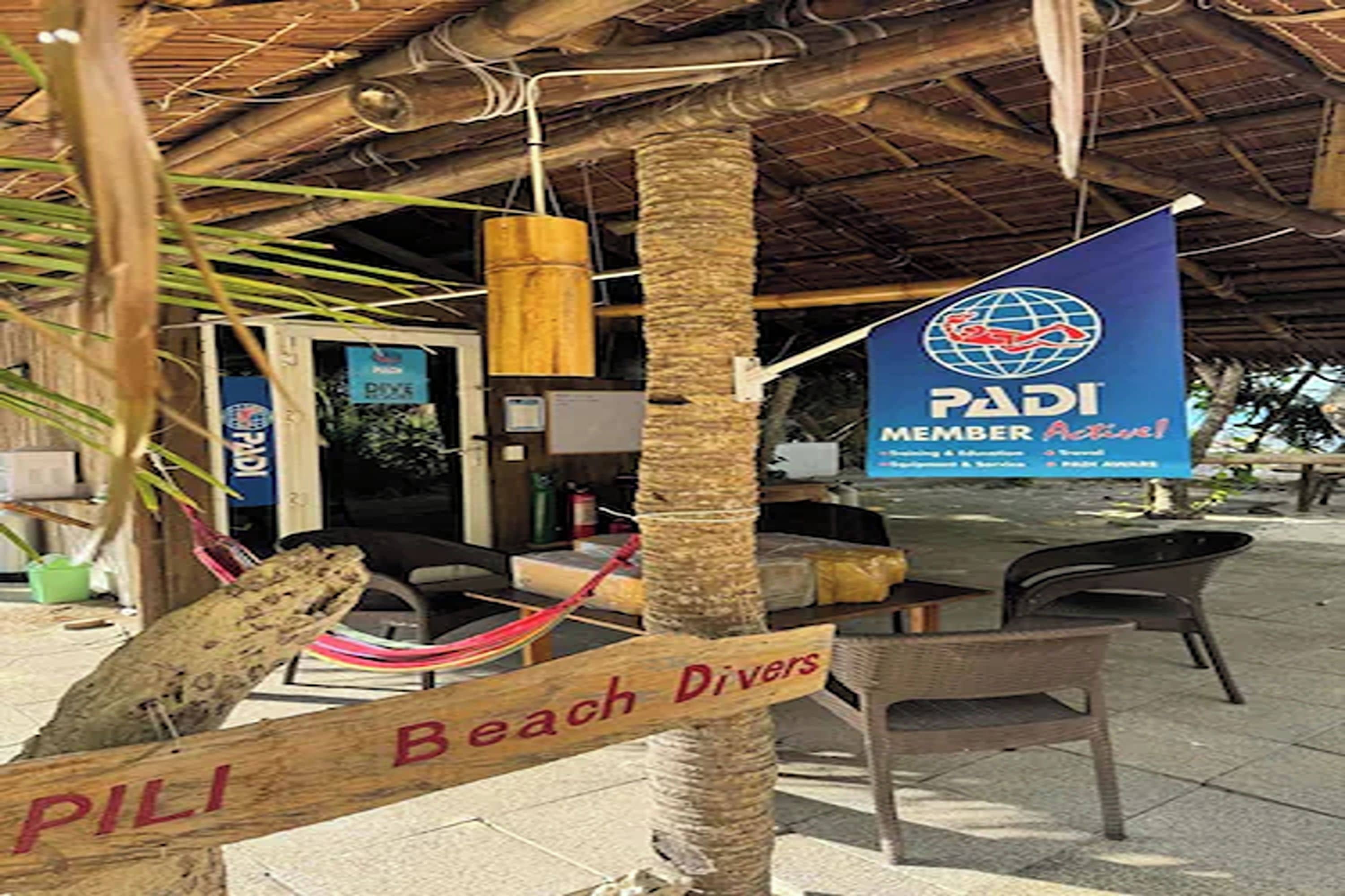 A beachside setting with a sign reading "PILI Beach Divers" and a PADI member banner.