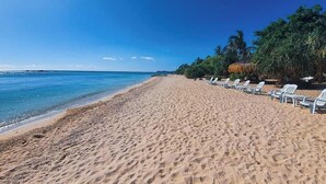 A beach with white lounge chairs and a clear blue sky. - Pili Beach Resort Agmanic By Zuzu (Santa Fe)