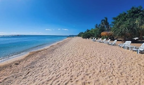 A beach with white lounge chairs and a clear blue sky. - Pili Beach Resort Agmanic By Zuzu (Santa Fe)