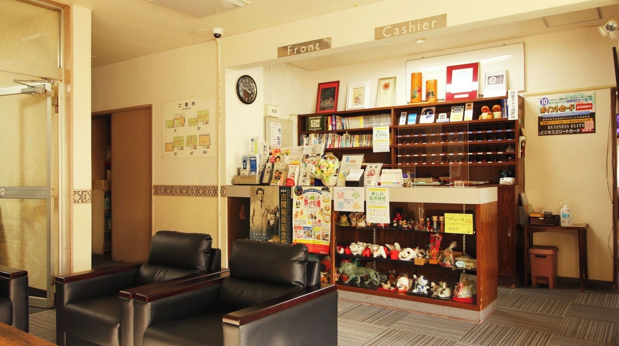 A hotel lobby with a cashier counter, seating area, and a wall with a clock and a map.