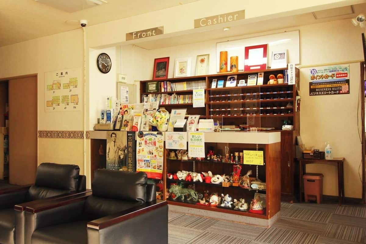 A hotel lobby with a cashier counter, seating area, and a wall with a clock and a map.