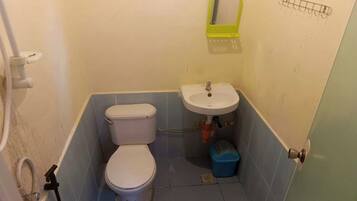 A small bathroom with a toilet, sink, and a window above the sink.
