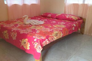 A bed with a floral bedspread, a swan-shaped towel, and a pink pillow. - Casa Paliton Siquijor Near Beach By Zuzu (San Juan)