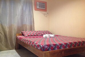 A single bed with a patterned bedspread, a wooden headboard, a wall-mounted air conditioning unit, and a curtain. - Casa Paliton Siquijor Near Beach By Zuzu (San Juan)