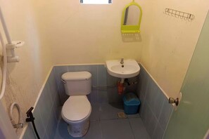 Un bagno piccolo con il water, un lavandino e una finestra sopra il lavandino.