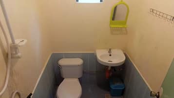 A small bathroom with a toilet, sink, and a window above the toilet.