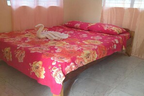 A bed with a floral bedspread, a swan-shaped towel, and matching pillows. - Casa Paliton Siquijor Near Beach By Zuzu (San Juan)