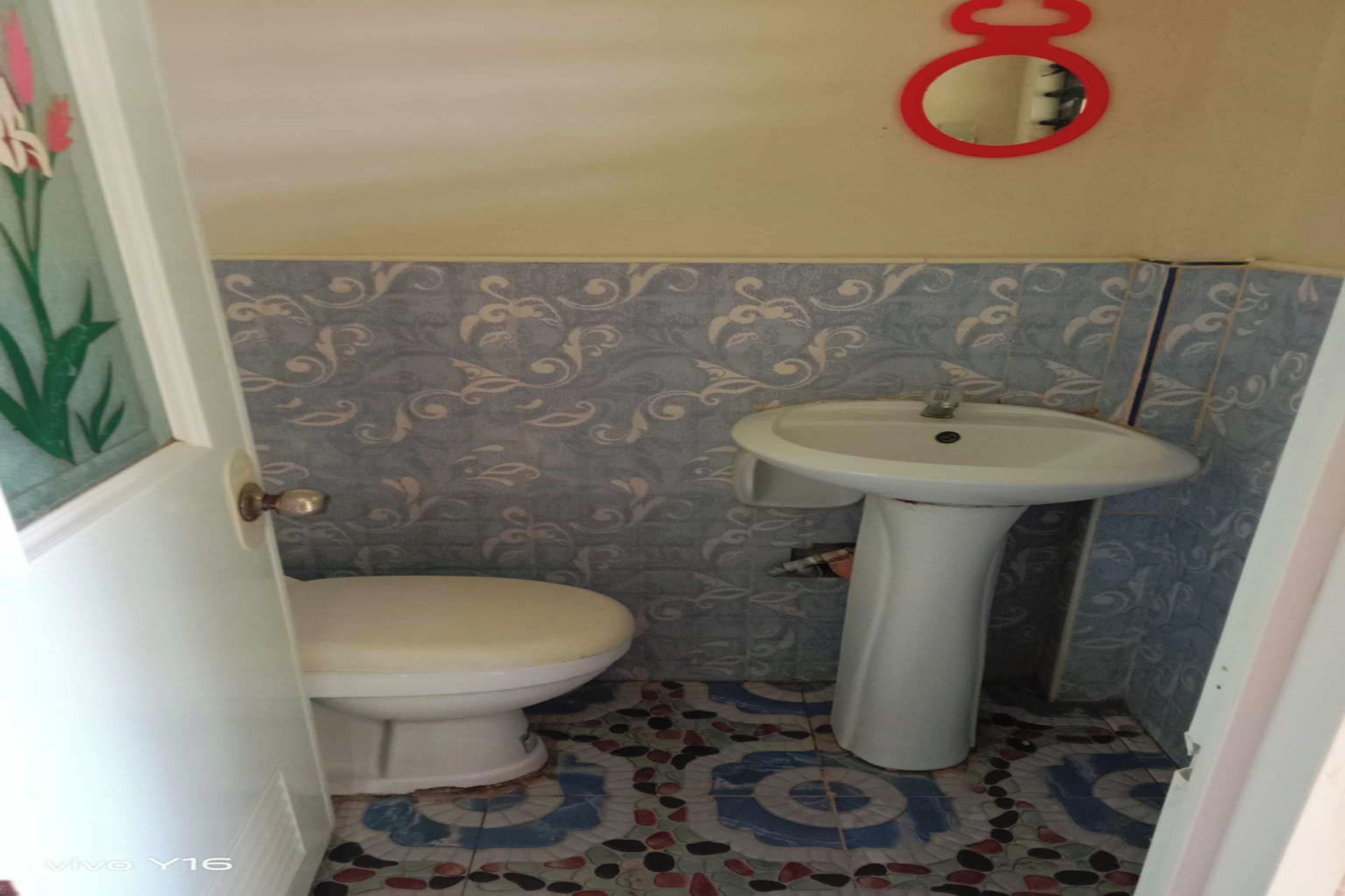 Un baño con inodoro, lavamanos y baldosas de suelo con diseño.