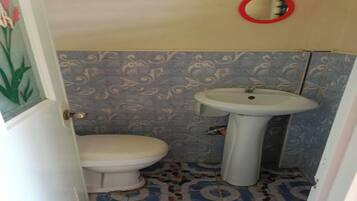 Un baño con inodoro, lavamanos y baldosas de suelo con diseño.