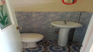 A bathroom with a toilet, sink, and patterned floor tiles. - Casa Paliton Siquijor Near Beach By Zuzu (San Juan)