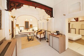 A spacious room with a sofa, a coffee table, and a desk with a lamp. - Gulab Haveli - Ihcl Seleqtions, Mandawa (Jhunjhunu)
