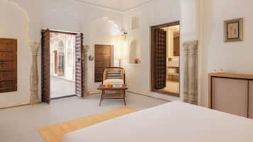 A room with a bed, a chair, and a desk. There are doors leading to other rooms.