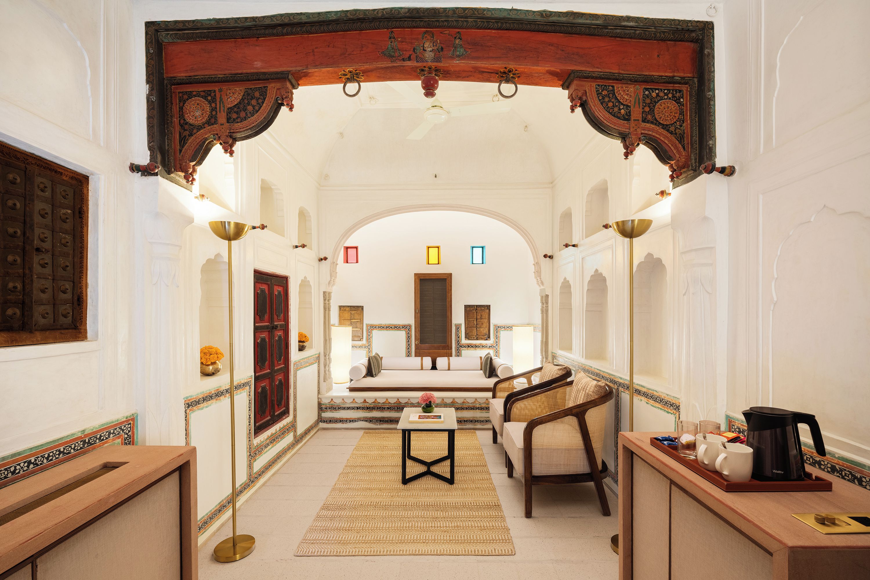 A corridor with a traditional archway, a sofa, a small table, and a coffee maker.