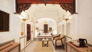 A corridor with a traditional archway, a sofa, a small table, and a coffee maker.