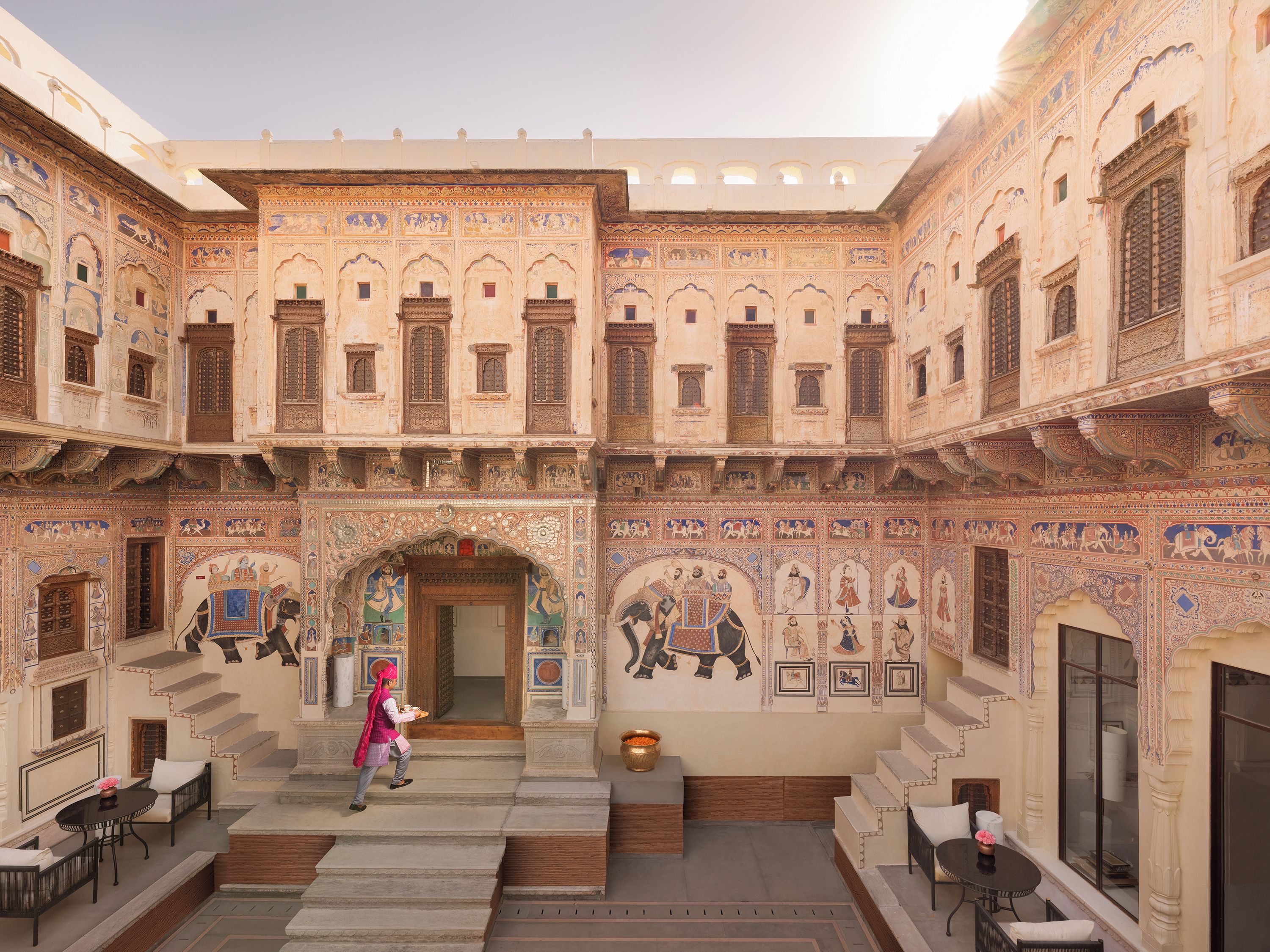 A courtyard with ornate architecture, a central staircase, and seating areas.