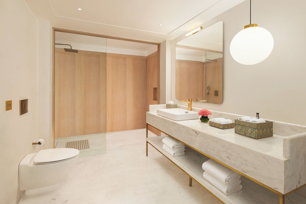 A modern bathroom with a white toilet, a large mirror, a vanity with a sink, and a shower area.