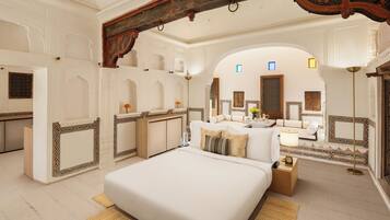 A spacious bedroom with a large bed, a sitting area with a sofa, and a vanity with a mirror.
