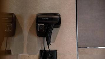 A hairdryer and a telephone mounted on a wall.