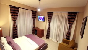 A hotel room with a bed, a desk, a TV, and a chair.