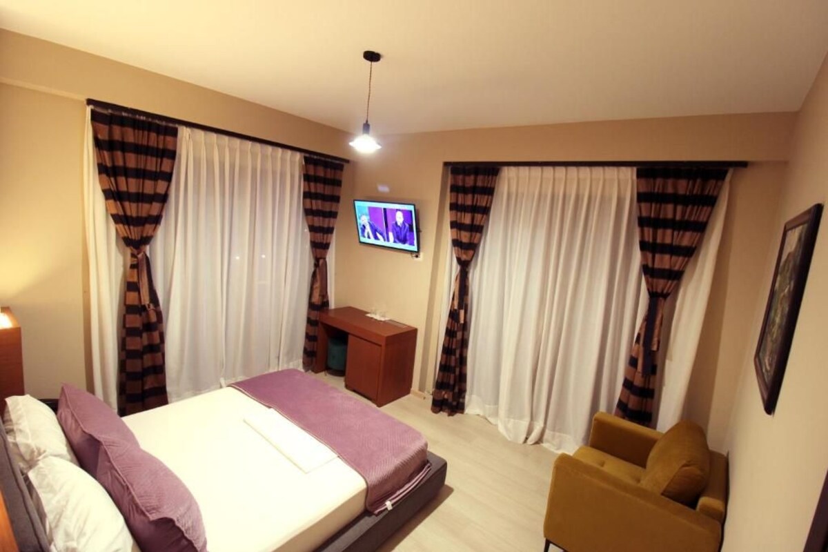 A hotel room with a bed, a desk, a TV, and a chair.