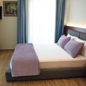 Une chambre d’hôtel avec un lit, une table de chevet et une fenêtre avec des rideaux.