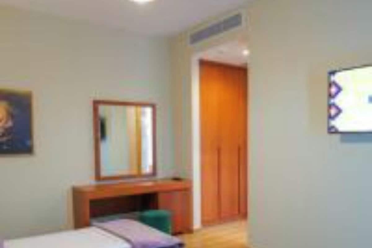 A bedroom with two beds, a desk, and a wardrobe.