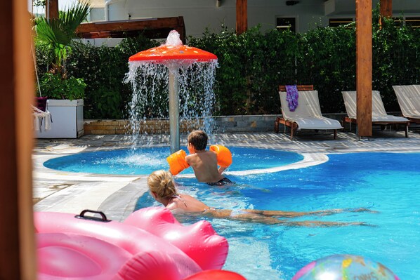 A swimming pool with lounge chairs and a water fountain.