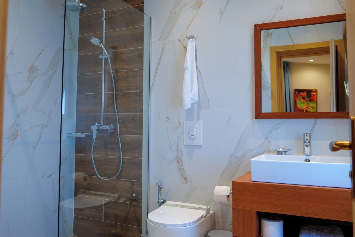 A modern bathroom with a glass-enclosed shower, a white sink, and a wooden vanity.