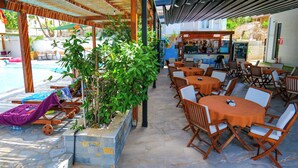 Zona exterior amb taules, caires, una piscina i un bar.