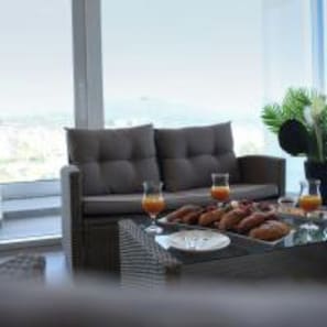 A modern living room with a sofa, a coffee table with breakfast items, and a view of the sea. - 6 Miles Hotel (Ksamil)