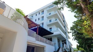 Edifici residencial modern de diverses plantes amb façana blanca, una zona exterior coberta i una escala que condueix als pisos superiors.